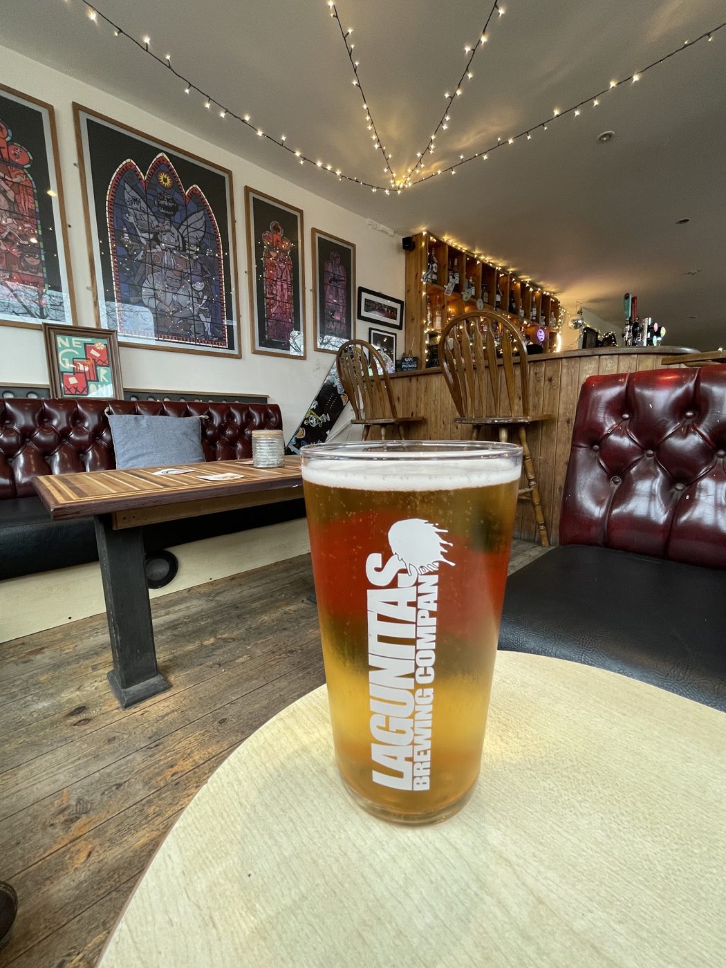 A pint of lager on a table, with fairy lights behind